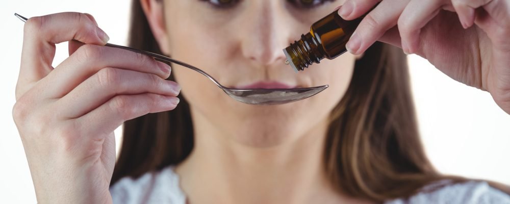 Pretty woman taking alternative tincture on white background
